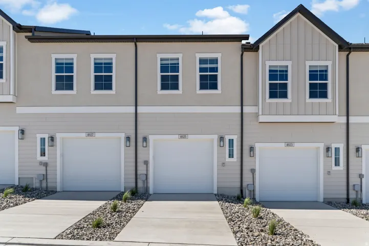 Townhome exterior featuring light-toned siding, stucco, and a gabled roofline