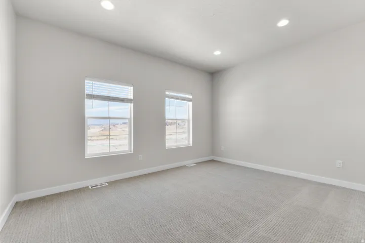Recessed lighting, light-toned walls, and neutral carpeting
