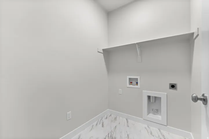 Dedicated utility space featuring a built-in shelf, light gray walls, and marble-look flooring