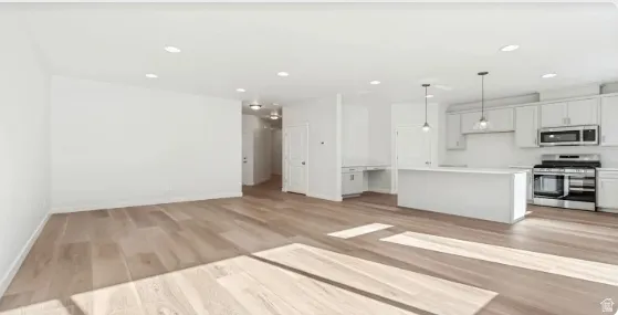 Open-concept living space featuring wide-plank wood-finish flooring and recessed lighting. This home is under construction, the pictures are of a similar home