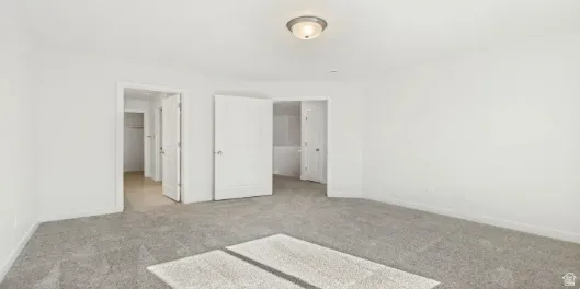 Spacious room featuring neutral carpeting and white painted walls. This home is under construction, the pictures are of a similar home