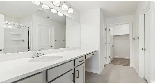 Dual-sink vanity with white countertop, chrome fixtures, and integrated mirror. This home is under construction, the pictures are of a similar home