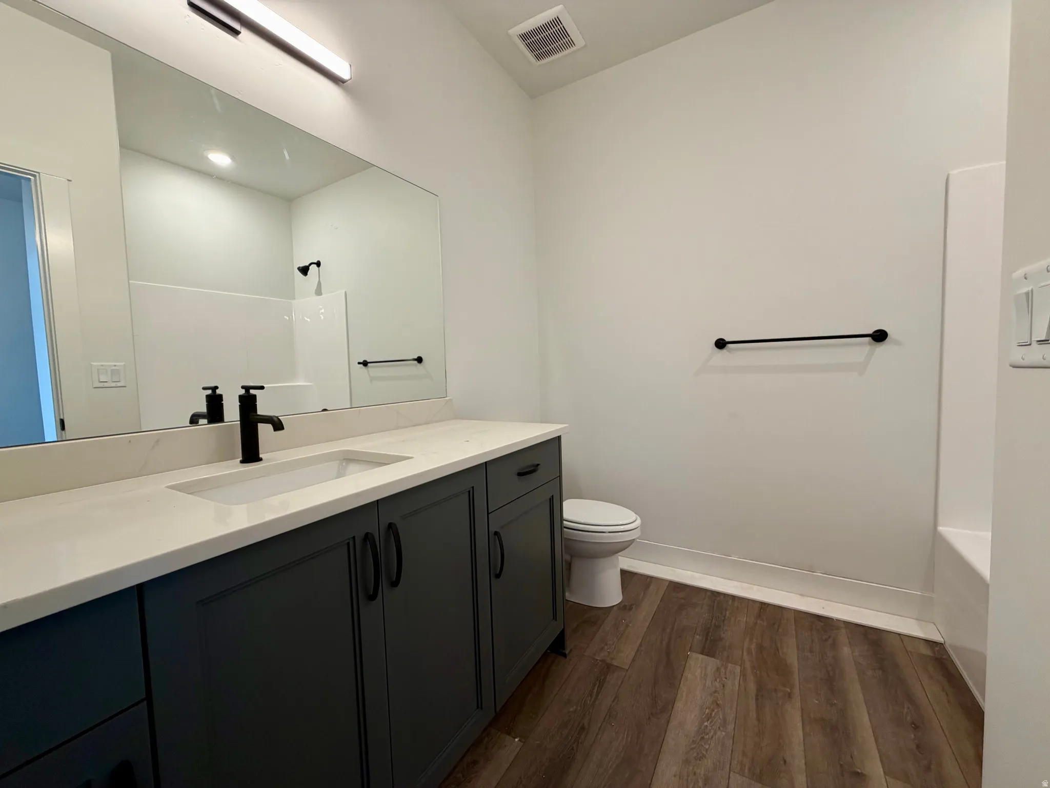 Bathroom featuring a dark wood-finish vanity with a light countertop, an integrated sink, and a matte black faucet