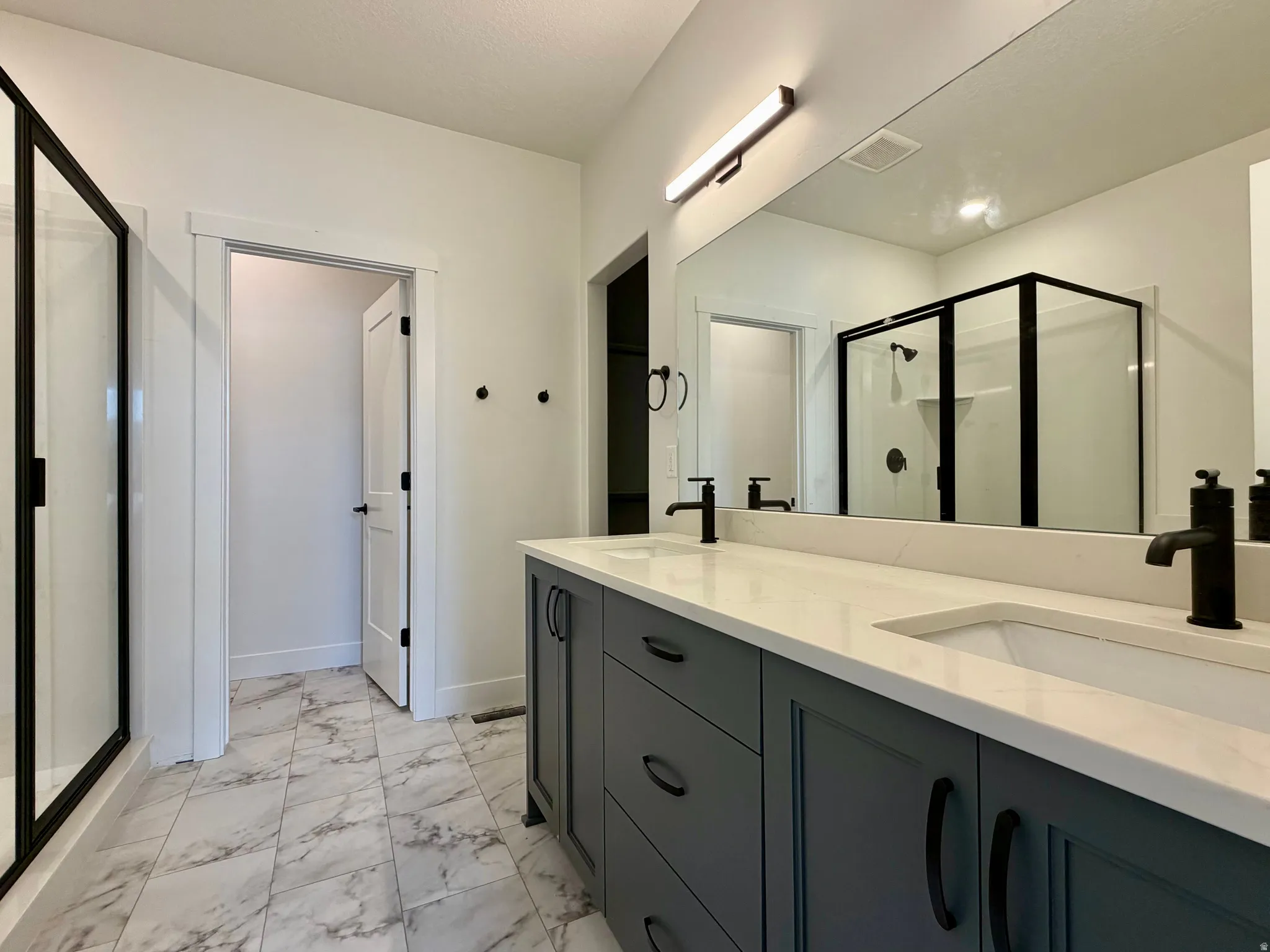 Dual vanity with matte black fixtures, white countertop, and gray cabinetry