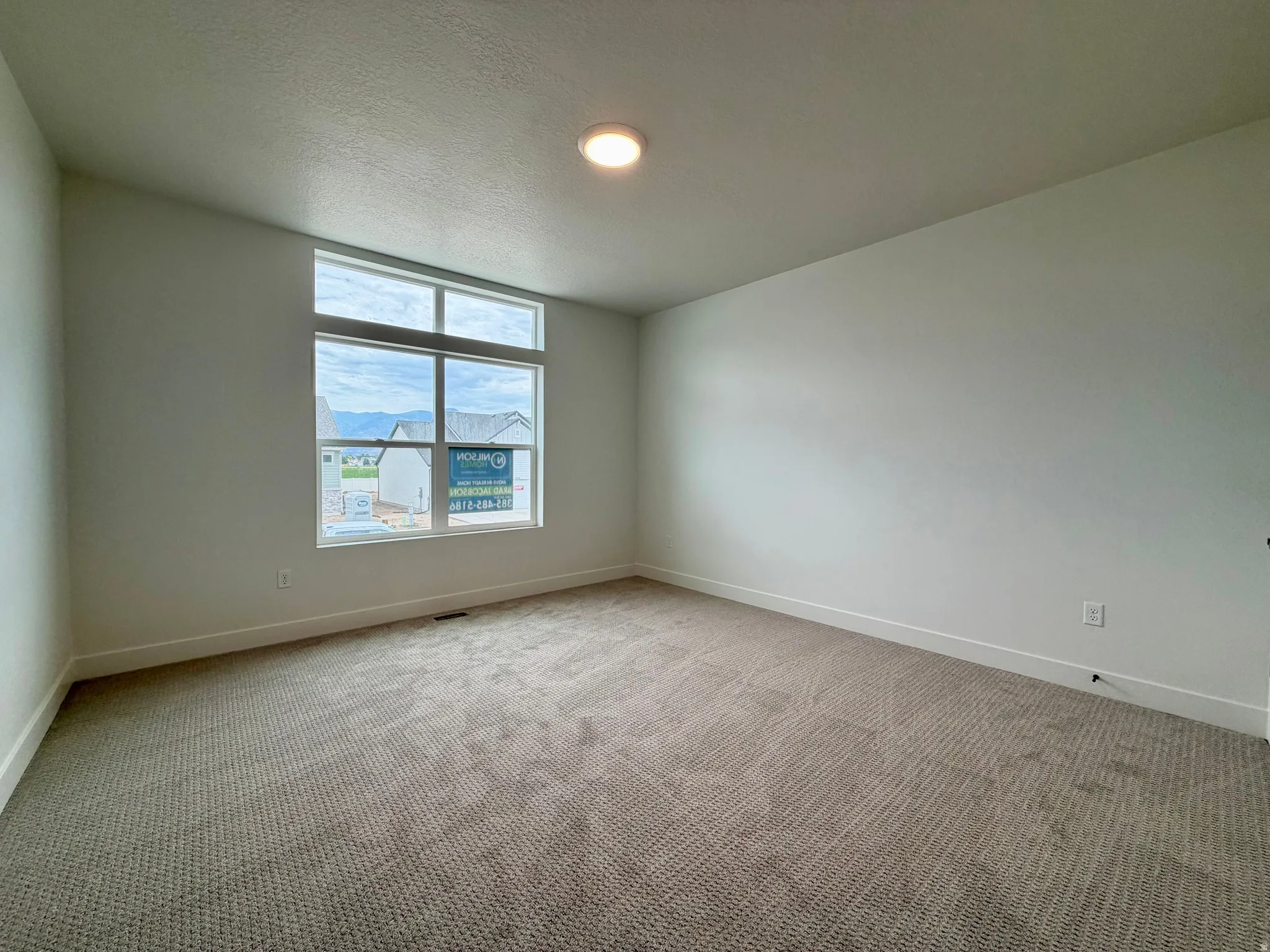 Carpeted room with a large multi-pane window and transom