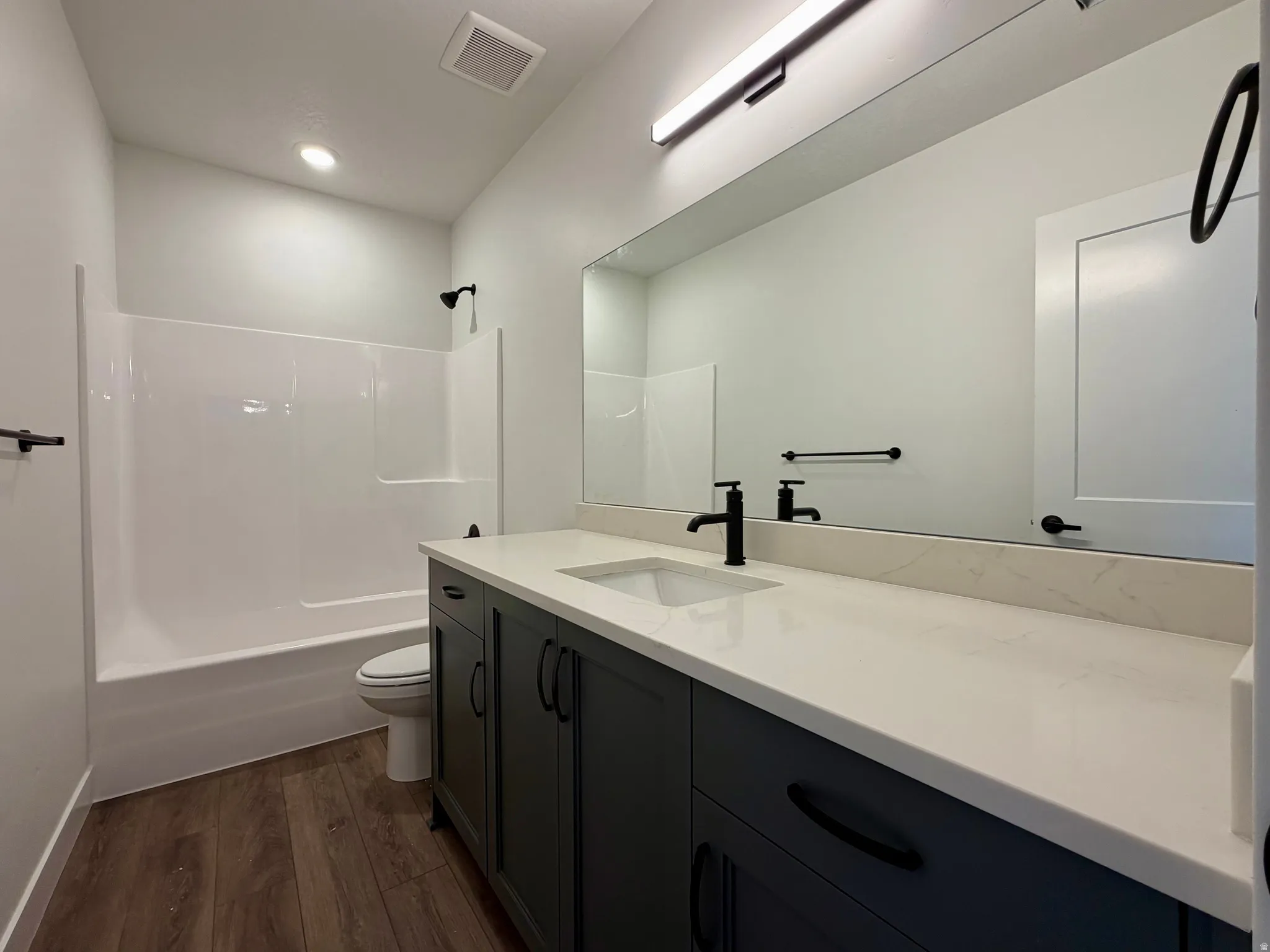 Bathroom featuring a large vanity with dark cabinetry, integrated sink, and light countertop