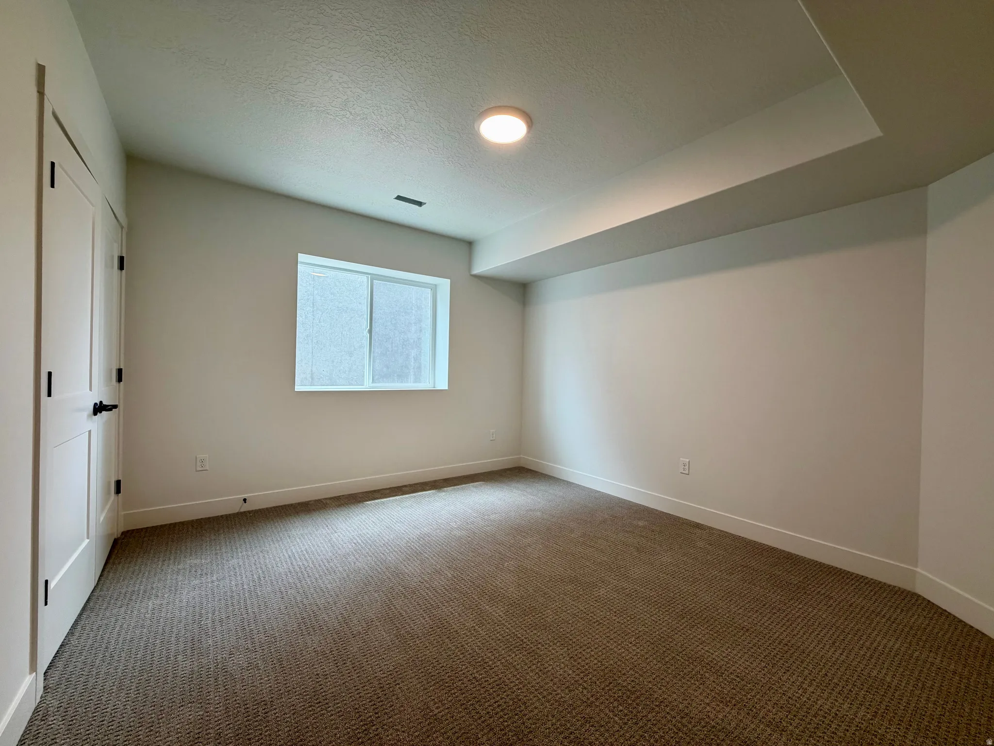 Carpeted room featuring a single window, recessed lighting, and a white paneled door with black hardware
