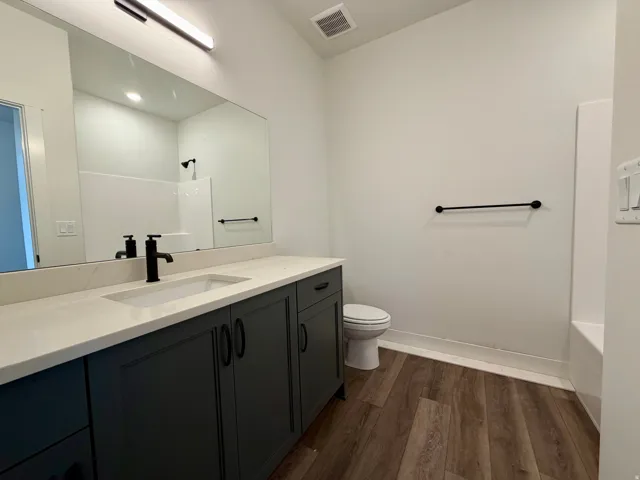 Bathroom featuring a dark wood-finish vanity with a light countertop, an integrated sink, and a matte black faucet