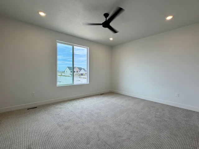 Spacious room featuring a large window, recessed lighting, and a modern ceiling fan