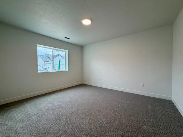 Carpeted interior room featuring a window with white trim, recessed ceiling lighting, and white baseboards