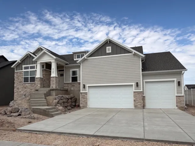Contemporary residence featuring a stone and siding exterior, a prominent covered entry with columns, a multi-pane window design, and an attached two-car garage with individual doors