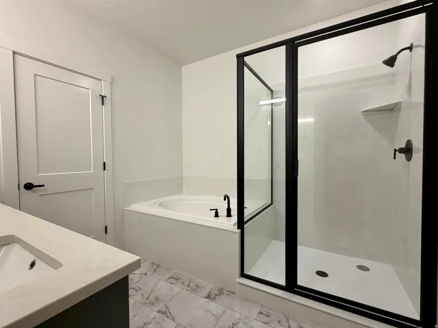 Modern bathroom featuring a black-framed glass shower enclosure, a built-in soaking tub, a single vanity with a white countertop, and marble-look floor tiling