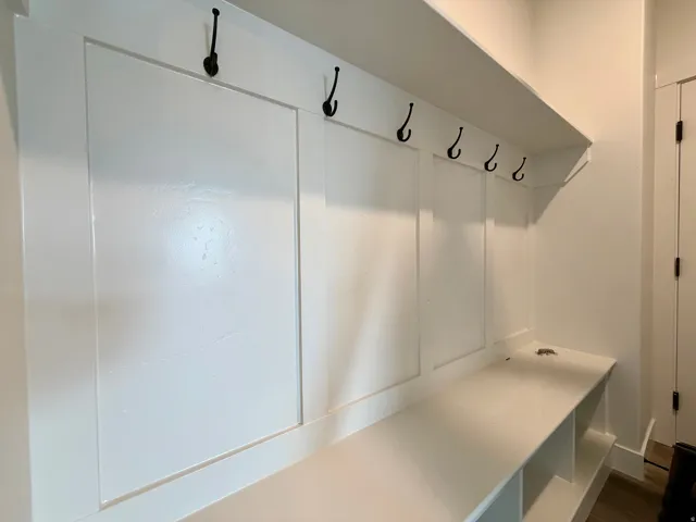 Built-in mudroom bench with cubby storage, upper shelving, and six wall-mounted coat hooks