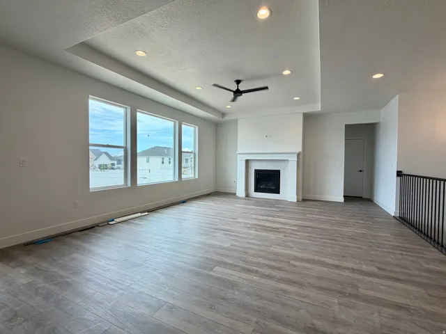 Spacious room with wood-finish flooring, a contemporary fireplace with white hexagon tile surround, and an elegant mantel