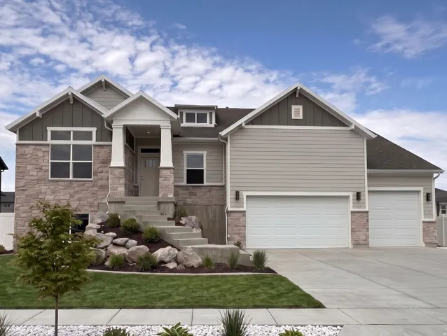 Contemporary exterior featuring stone accents, siding, a covered entry, and a two-car garage with an additional single-car garage