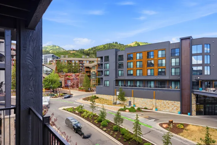 Modern building exterior with a mountain backdrop, featuring a mix of dark paneling and wood-finish accents