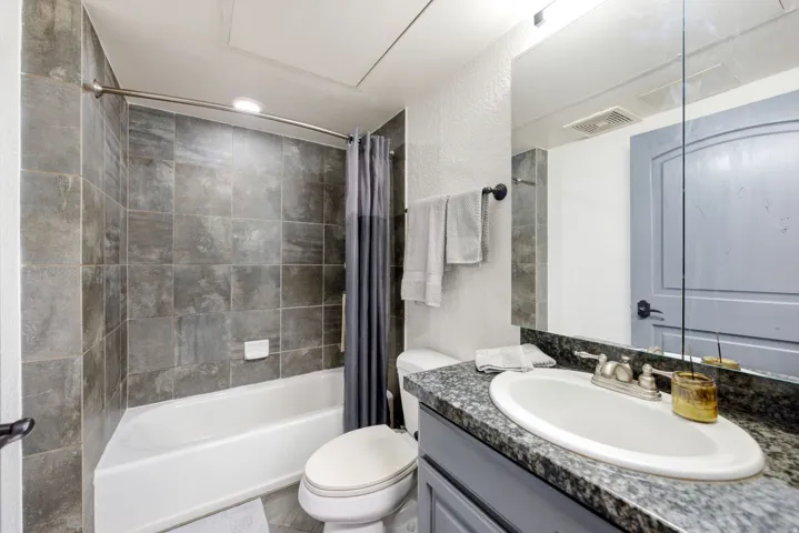 Bathroom featuring a tub/shower combination with tile surround, a vanity with a granite-style countertop, an oval undermount sink, and a framed mirror