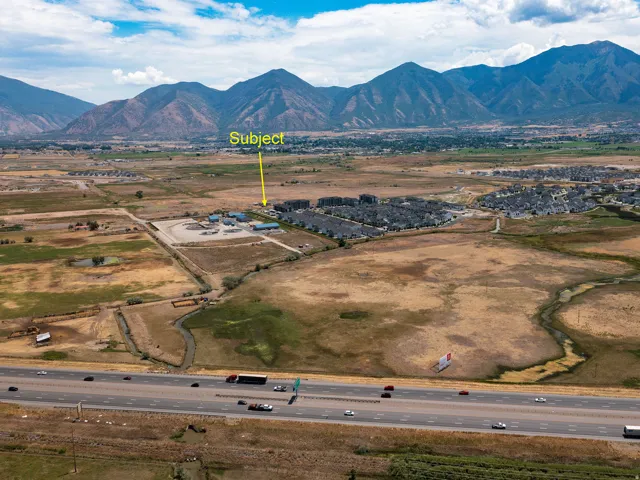 Aerial perspective showcasing a property surrounded by expansive undeveloped land, with mountain ranges forming the horizon