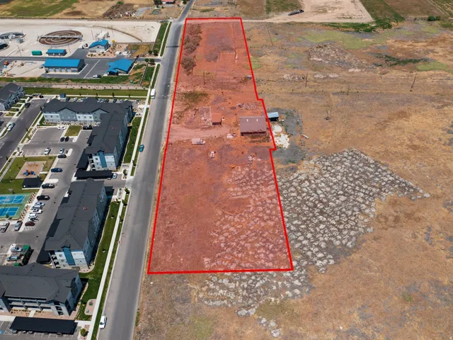 Expansive undeveloped land parcel featuring existing structures, positioned alongside a paved thoroughfare