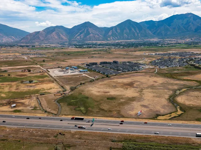 Expansive landscape featuring distant mountains, a multi-lane highway, and a residential development