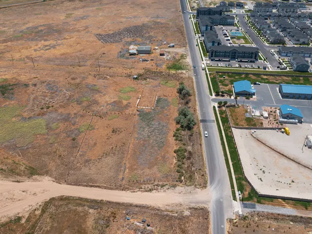 Expansive undeveloped land parcel featuring a visible road frontage, existing utility poles, and surrounding established residential and commercial properties