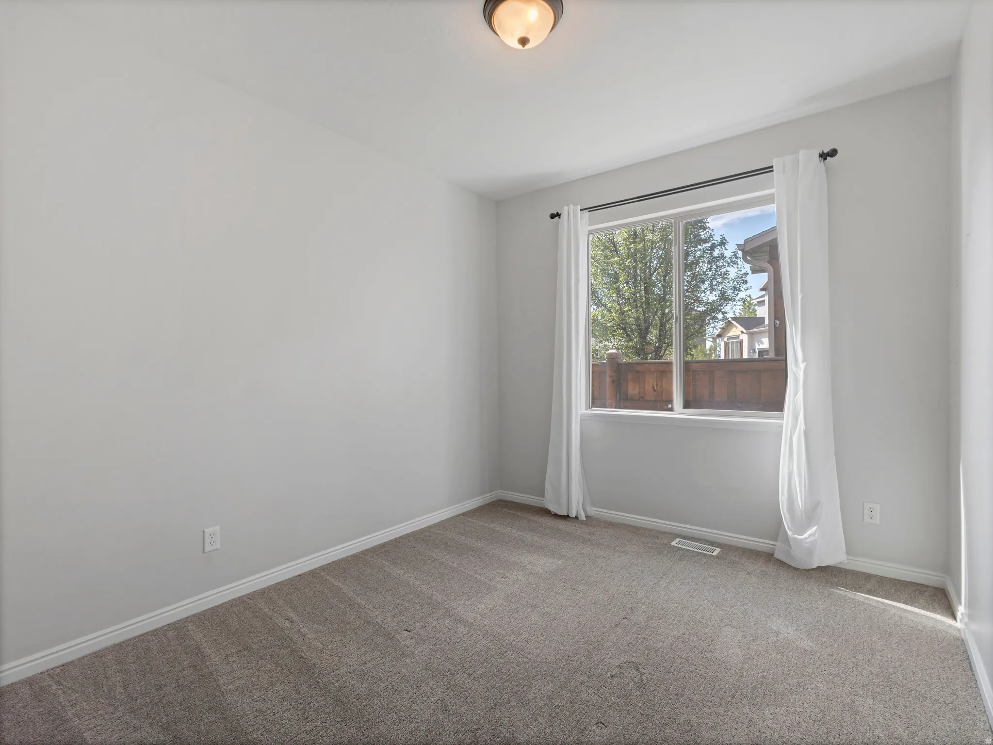 Neutral gray walls, wall-to-wall carpeting, and a large window with white trim