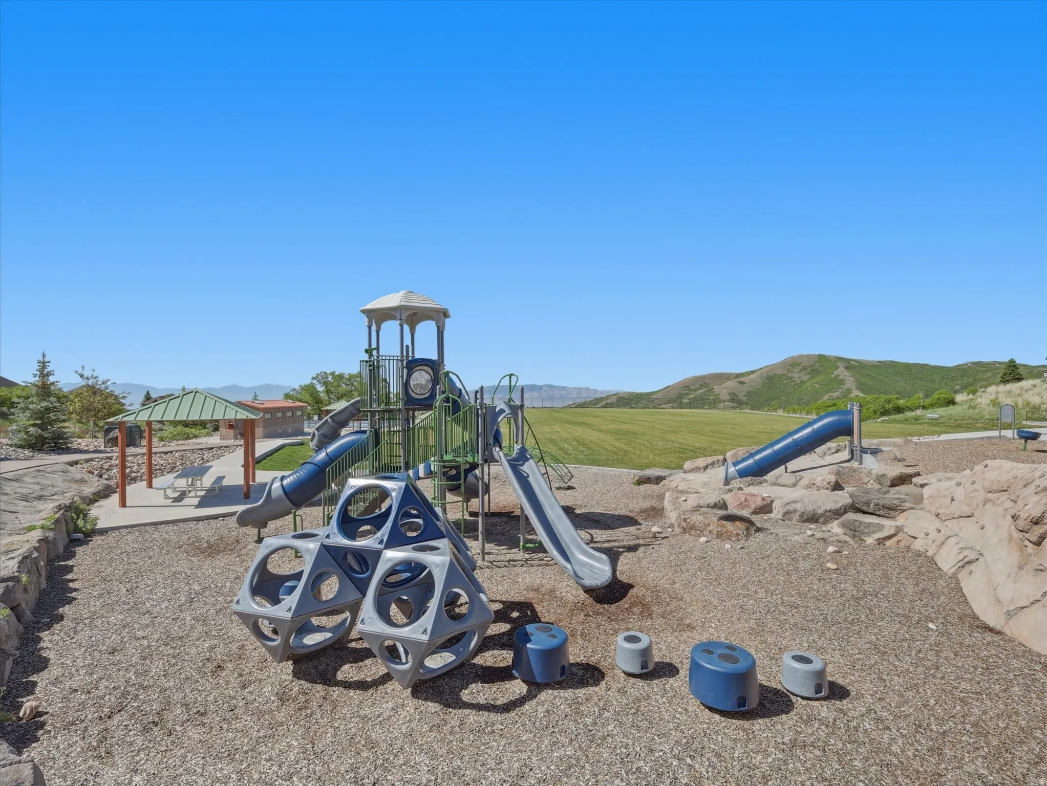 Playground area featuring multiple slides, climbing structures, and a wood chip surface
