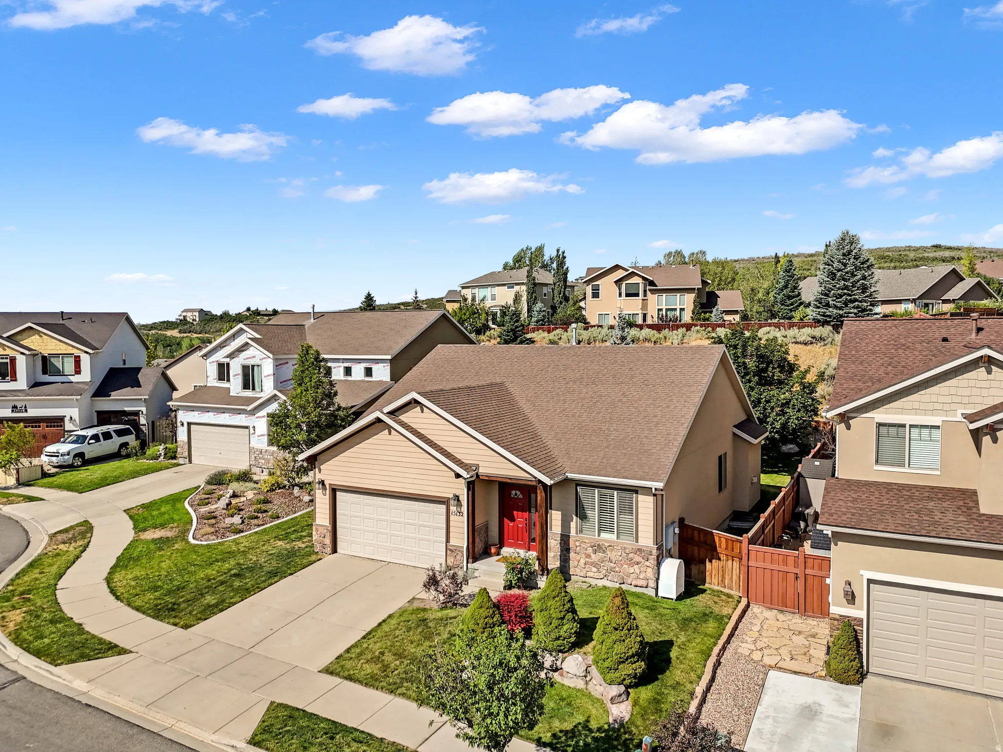 Single-story residence featuring a two-car garage, red entry door, and stone facade accents