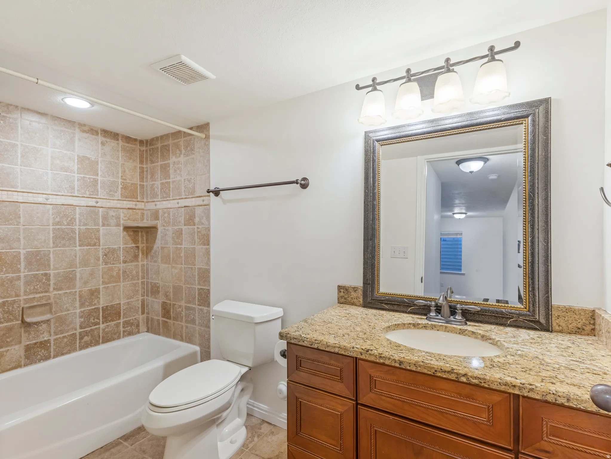 Bathroom featuring a vanity with a granite-style countertop, undermount sink, and wood-finish cabinetry