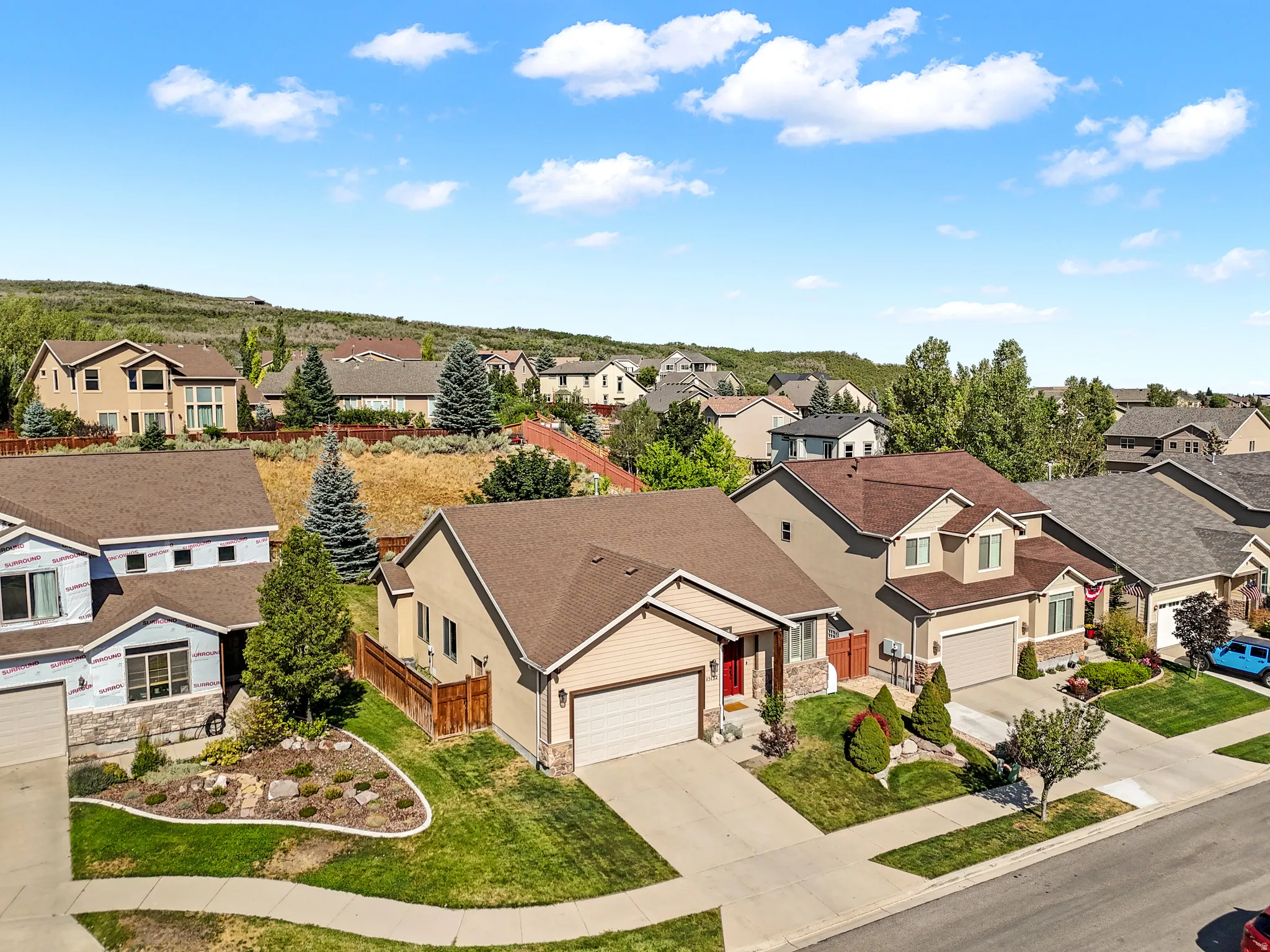 Single-story residence featuring a two-car garage, stone facade accents, and a red front door