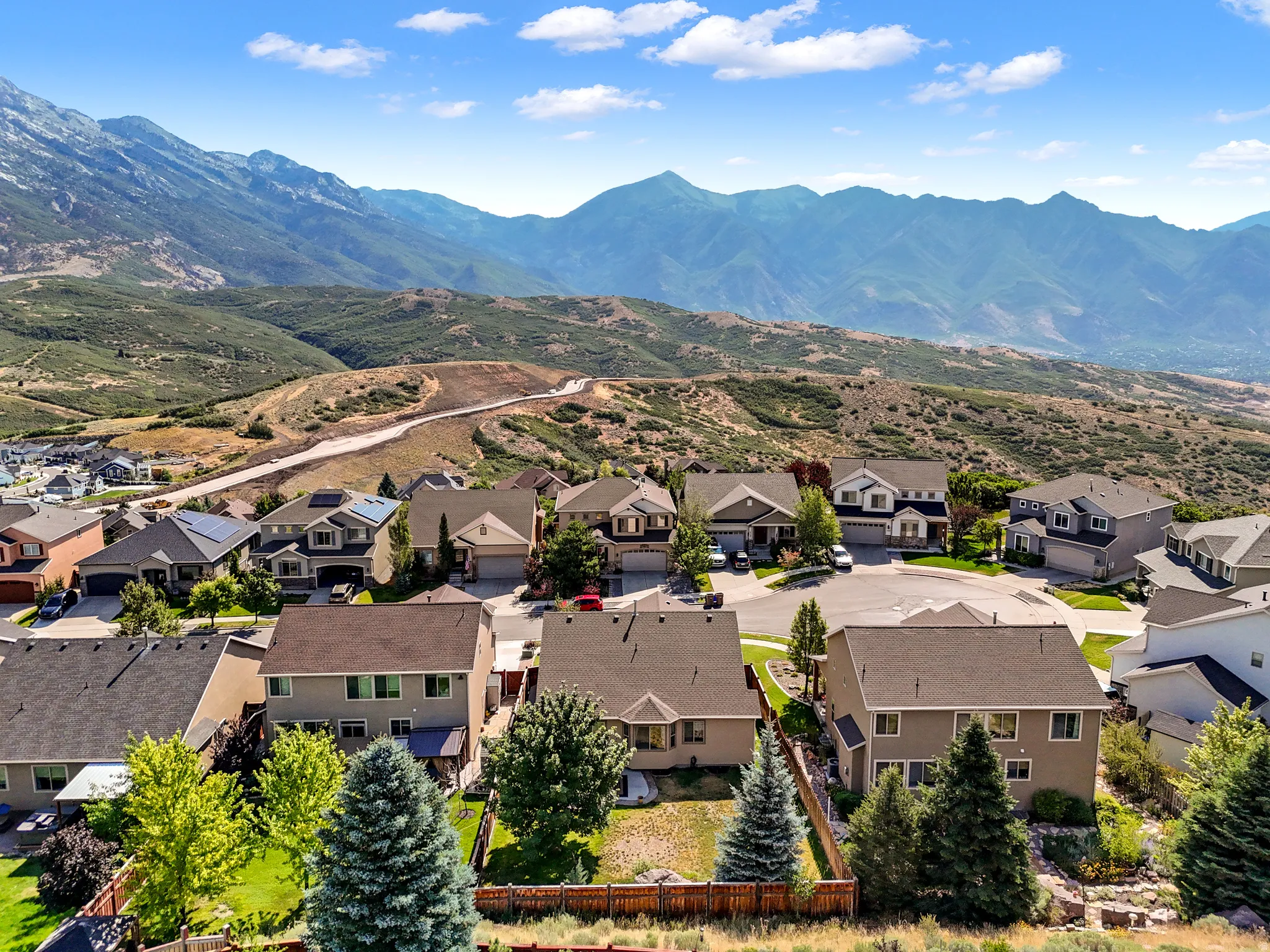 Residential neighborhood featuring varied home styles, mountain backdrop, and established landscaping