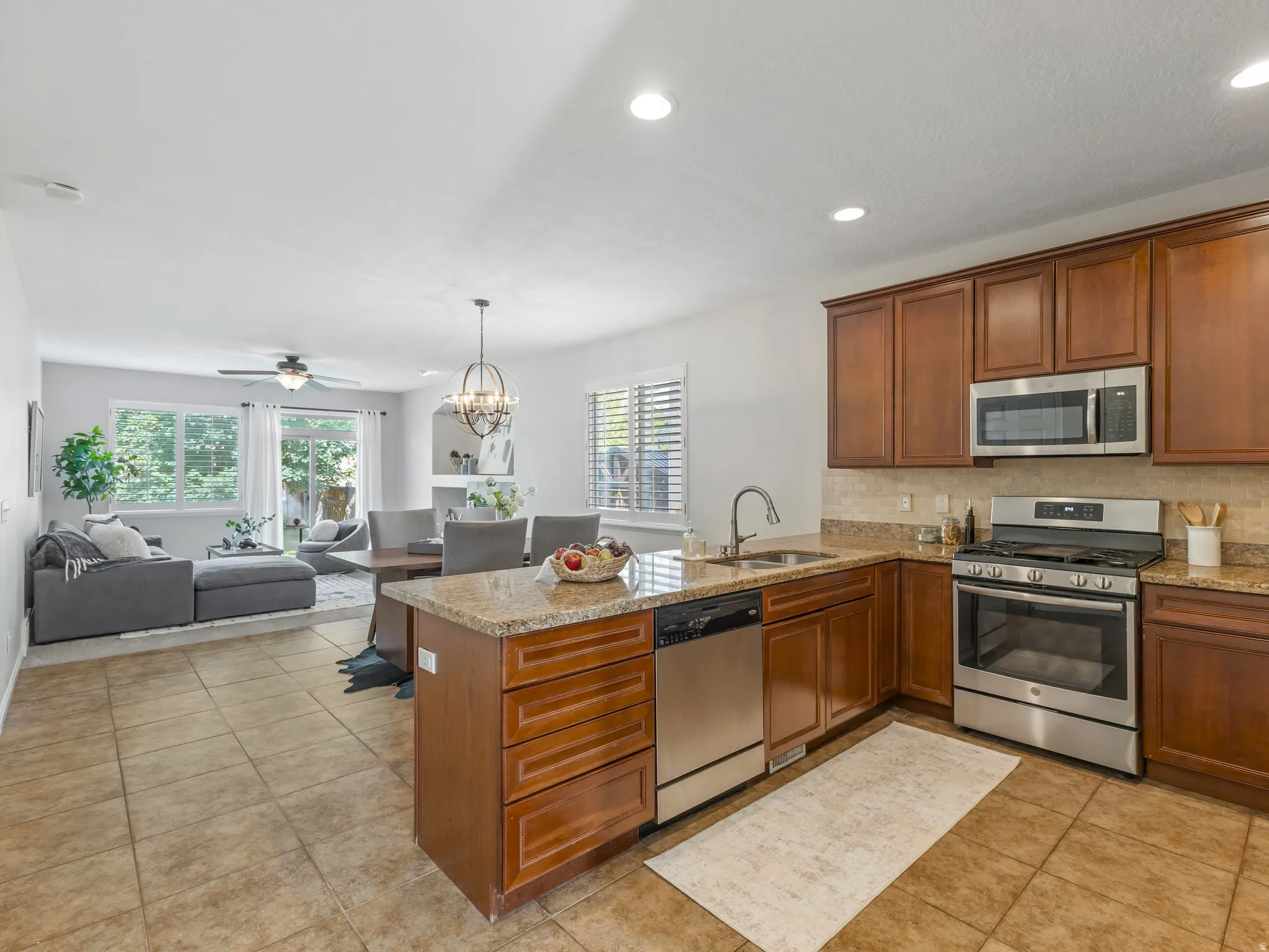 Kitchen featuring a granite countertop island with integrated sink, stainless steel dishwasher, and rich wood cabinetry