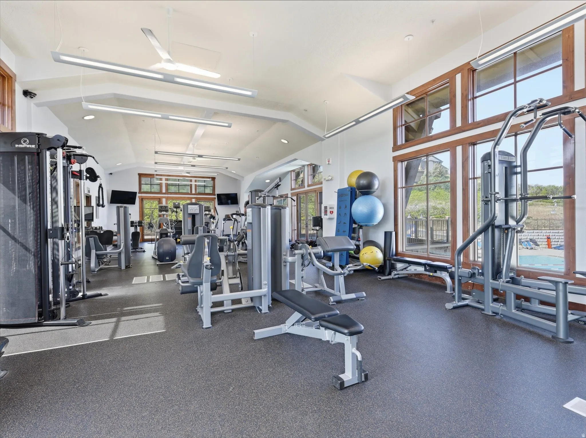 Spacious fitness center featuring high ceilings, ample natural light from large windows, and resilient rubber flooring