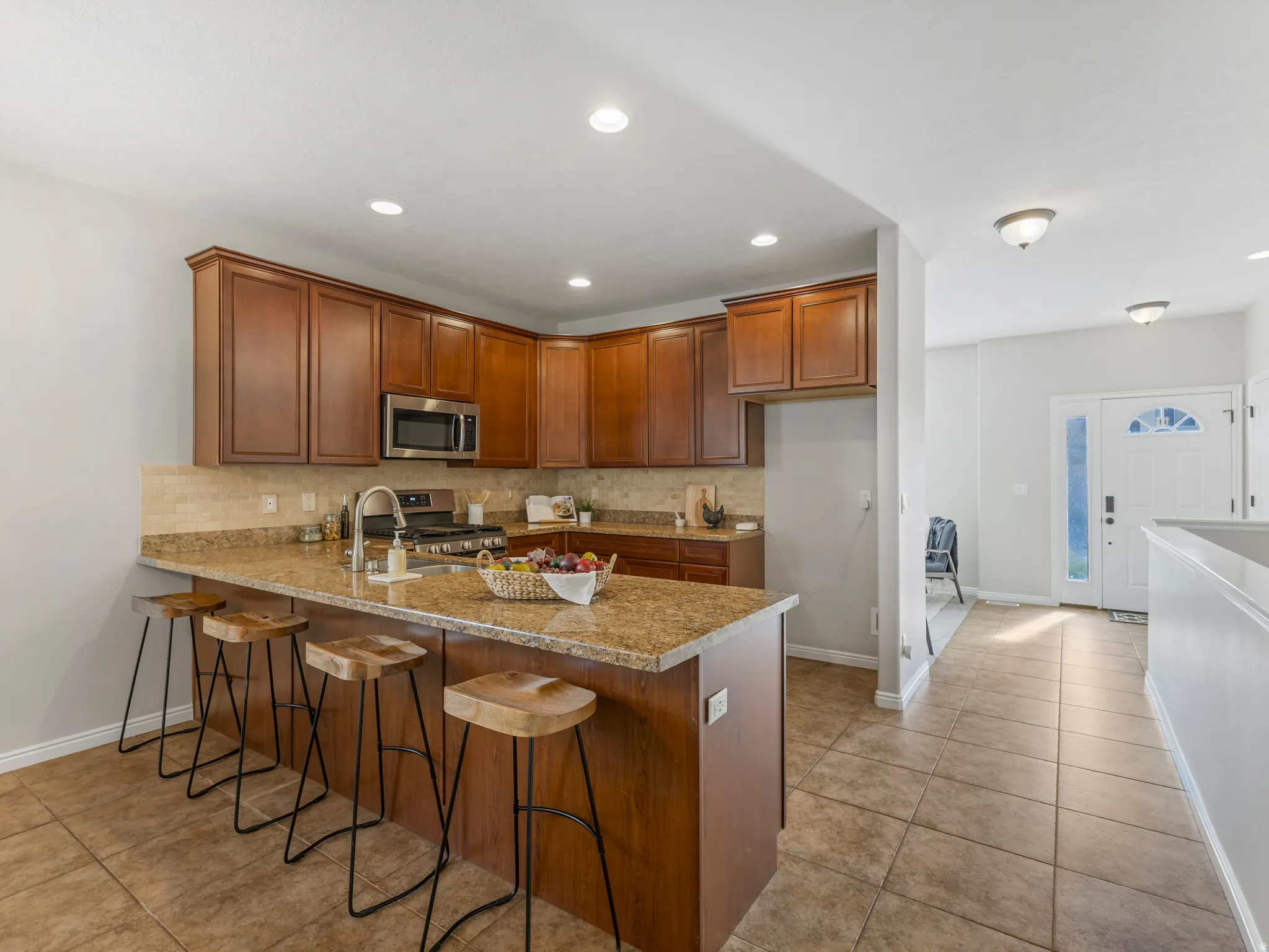 Kitchen featuring wood cabinetry, stainless steel appliances, granite countertops, and a tiled backsplash