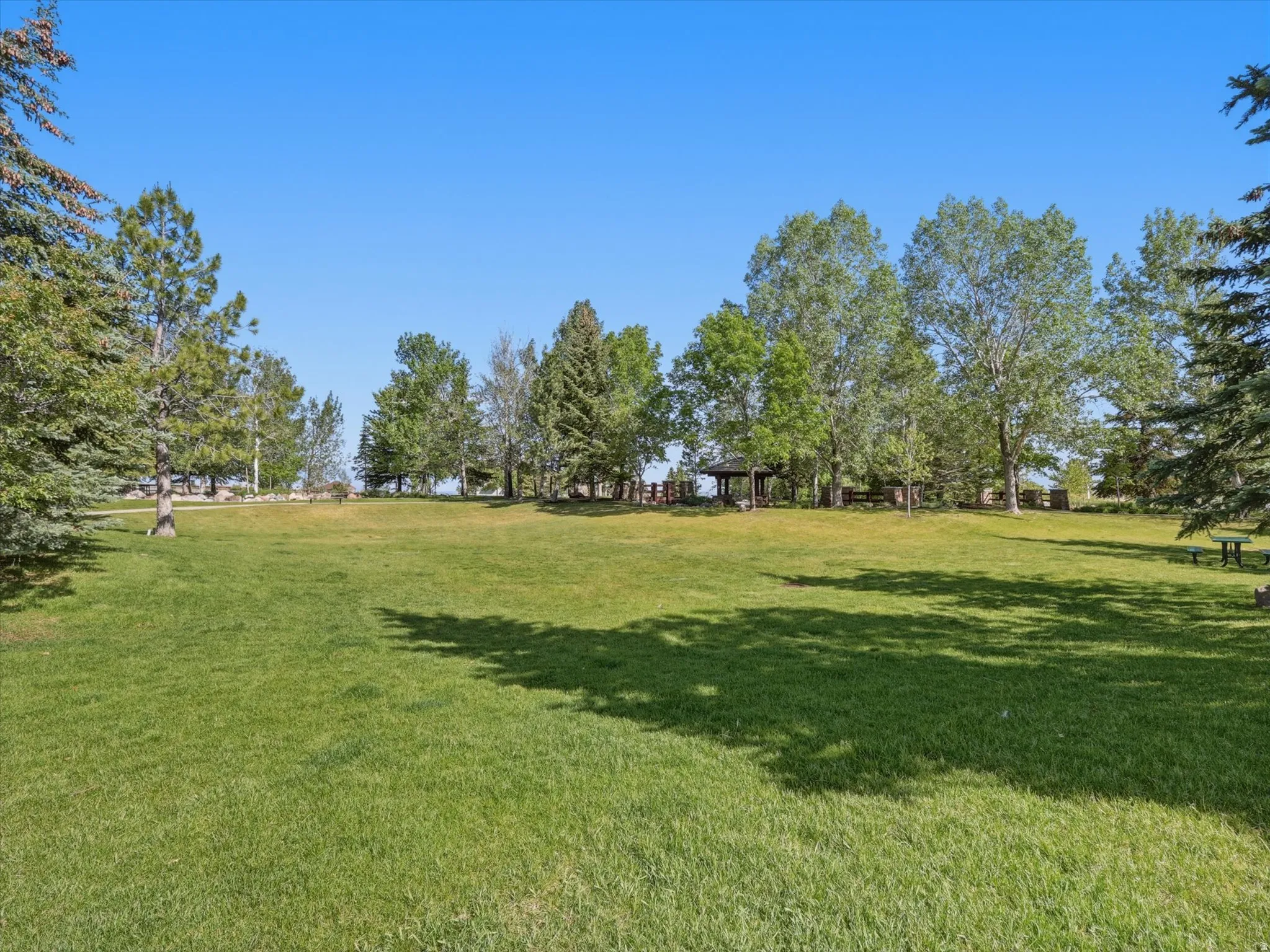 Expansive green lawn with mature trees and a distant gazebo