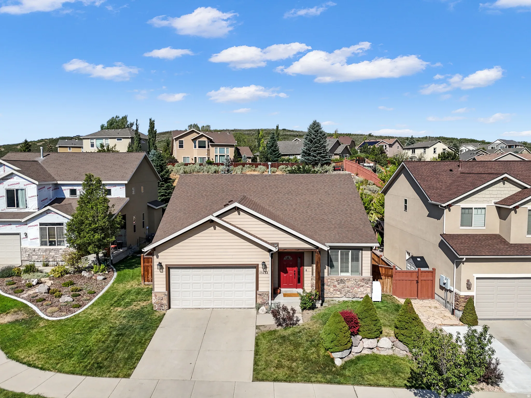 Craftsman-style residence featuring a two-car garage, stone façade accents, and a vibrant red entry door