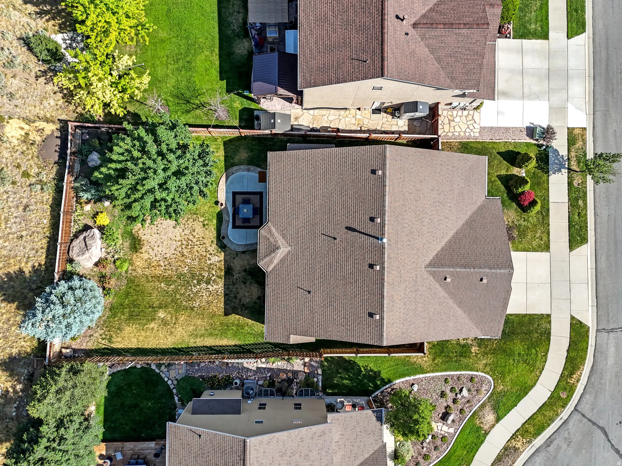 Expansive property featuring a multi-gabled roofline, concrete driveway, and a fenced backyard with a patio