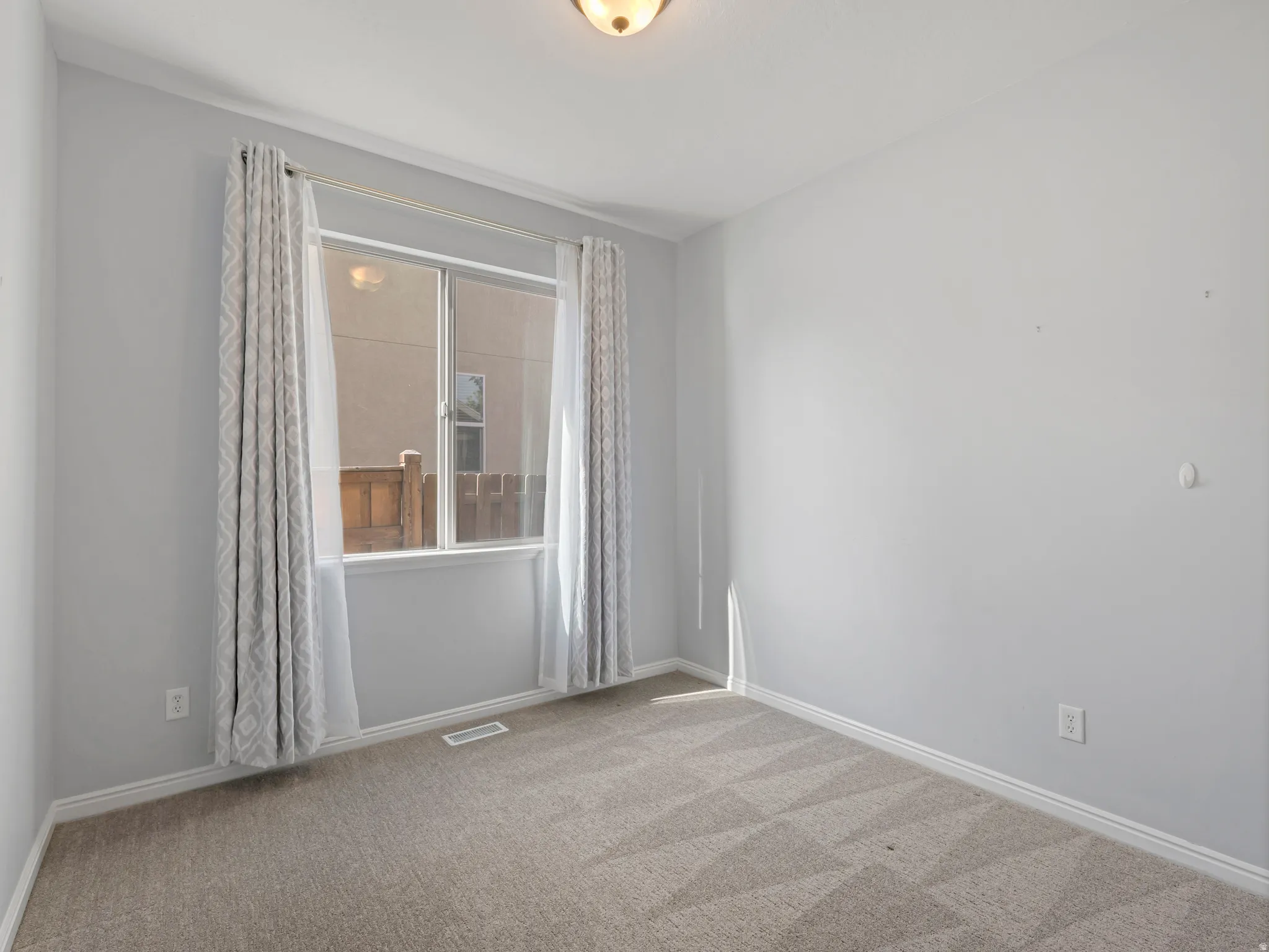 Carpeted room featuring light gray walls, white baseboards, and a single window with a built-in sill
