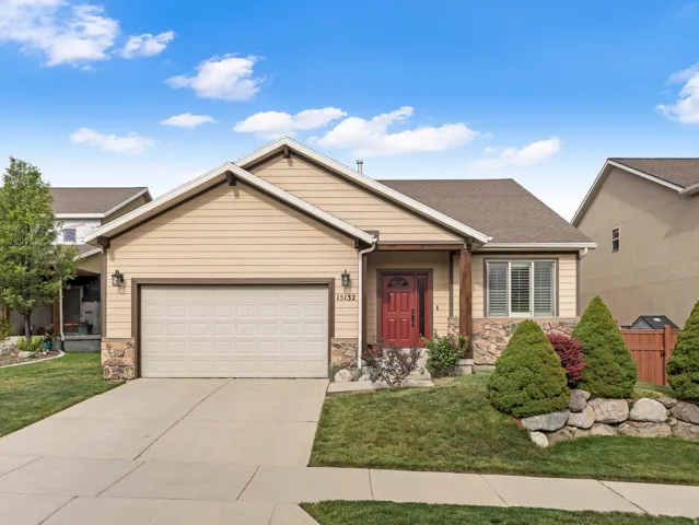 Single-story residence featuring light-colored siding, a prominent attached garage, and stone accents