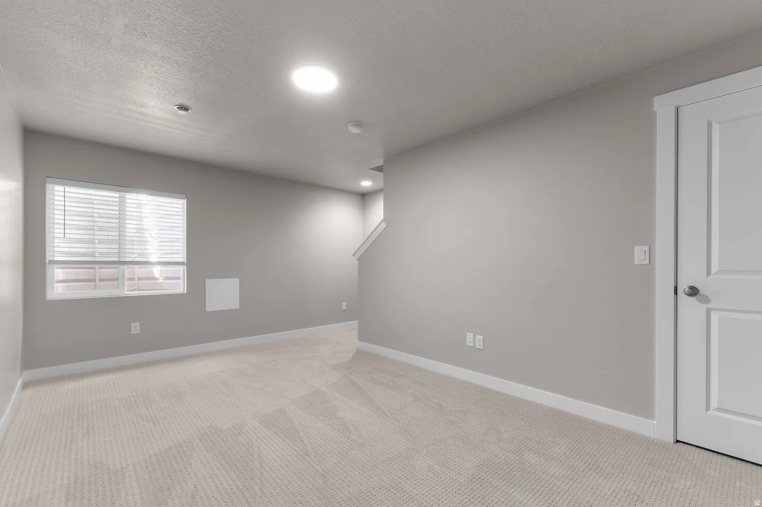 Recessed lighting, light-toned carpeting, white trim, window with blinds, and white interior door