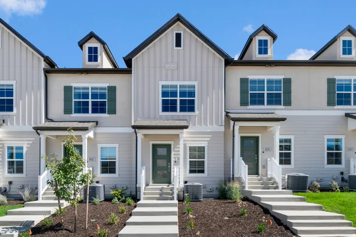 Modern townhome exterior featuring board and batten siding, multiple gables, dormer windows, and a covered entry