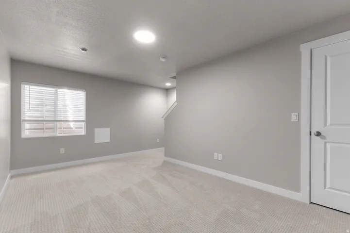 Recessed lighting, light-toned carpeting, white trim, window with blinds, and white interior door