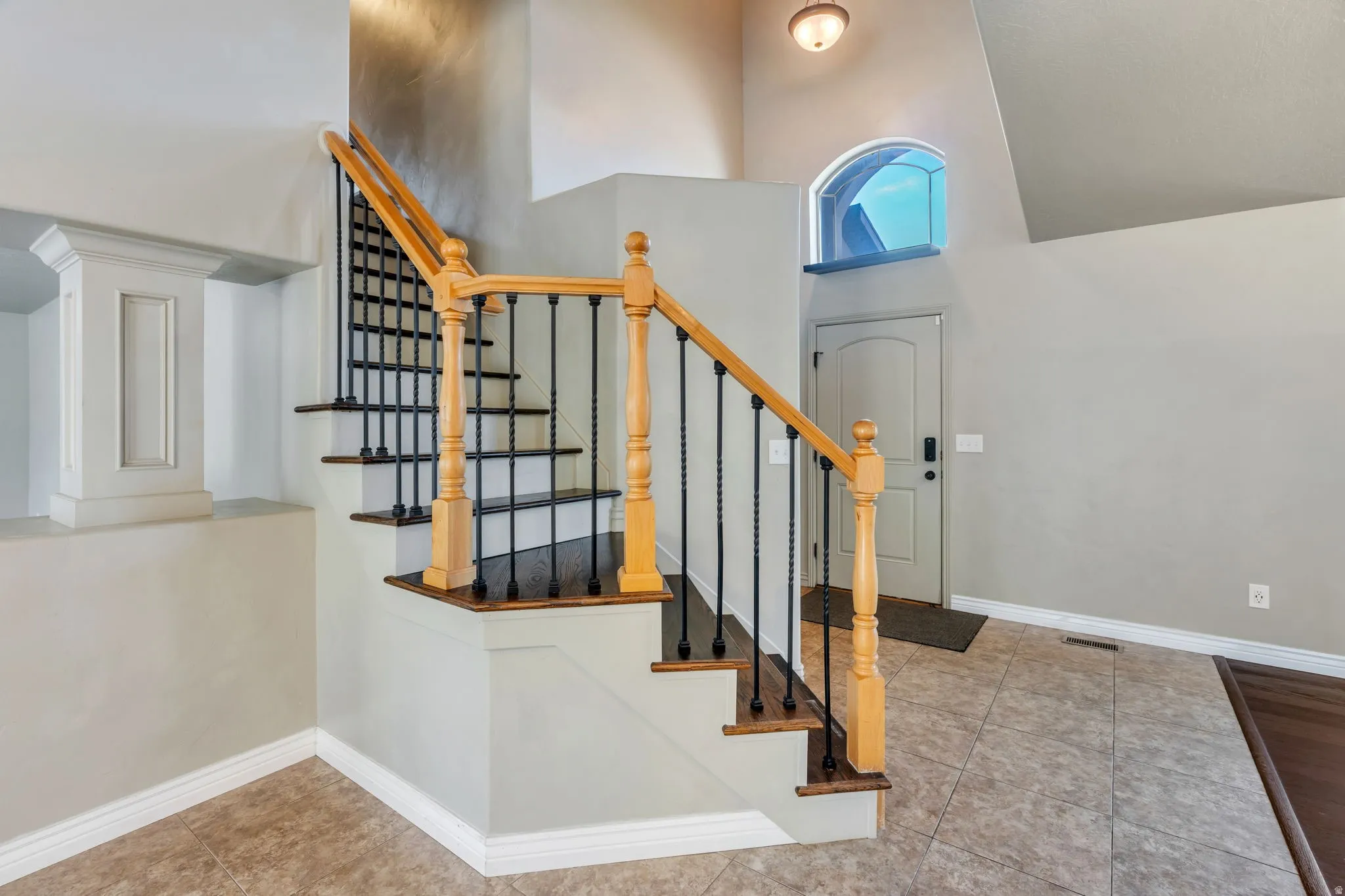 Entryway featuring a staircase with wood newel posts, black wrought iron balusters, and dark wood-finish treads