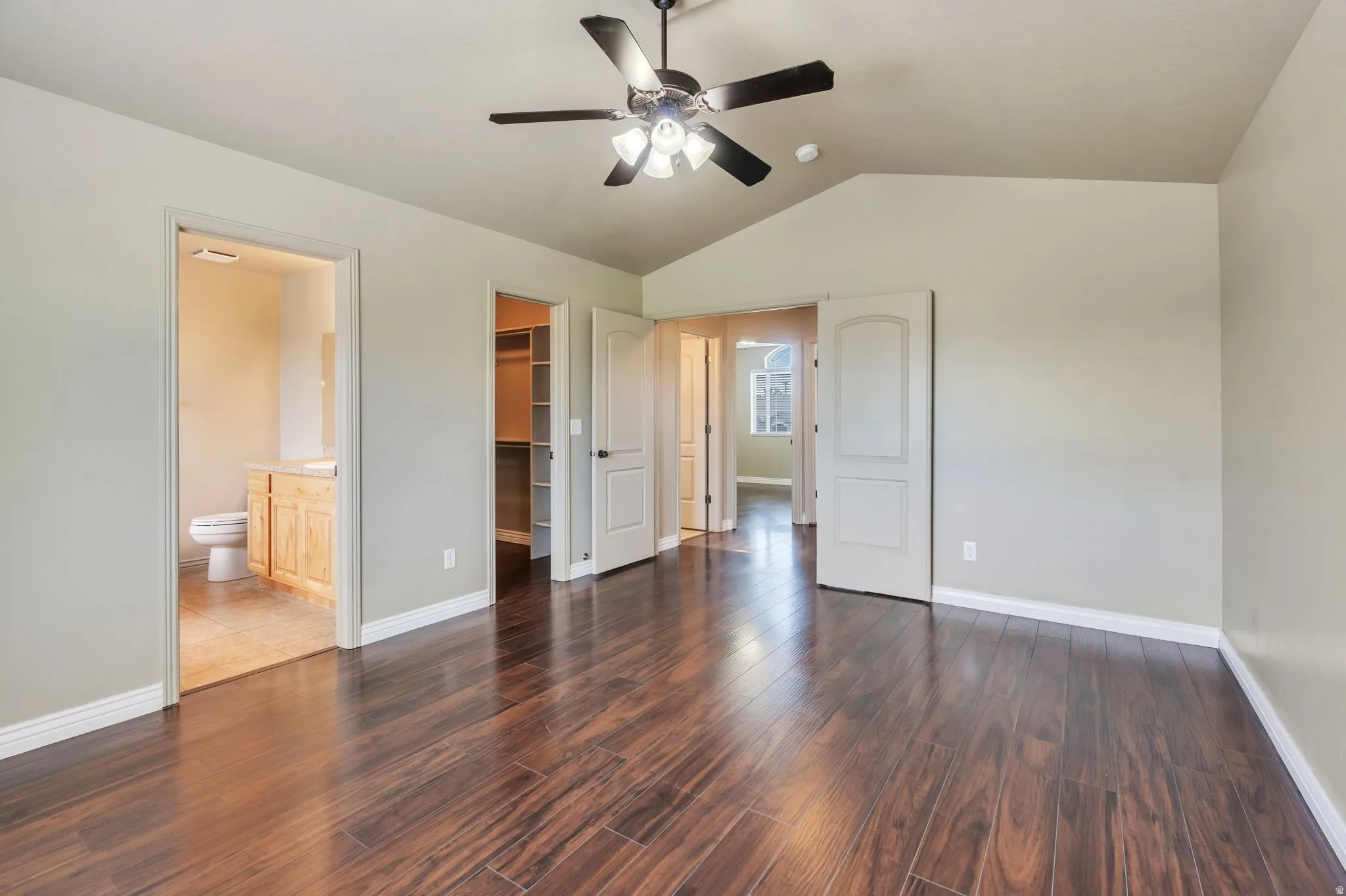 Spacious room featuring wood-finish flooring and a vaulted ceiling