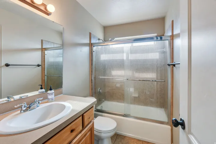 Bathroom featuring a single vanity with an integrated sink, wood-finish cabinetry, and a full-width mirror