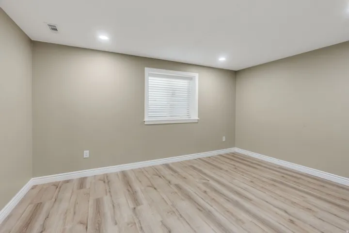 Room with light wood-finish flooring, neutral wall paint, and white baseboards