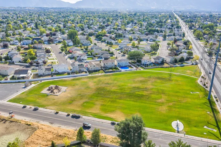 Expansive green space featuring a playground structure and surrounding residential area