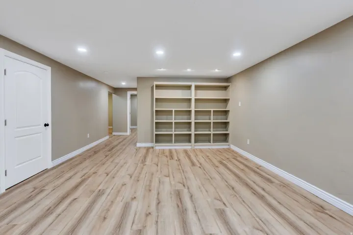 Spacious room featuring wood-finish flooring, recessed lighting, and a built-in shelving unit