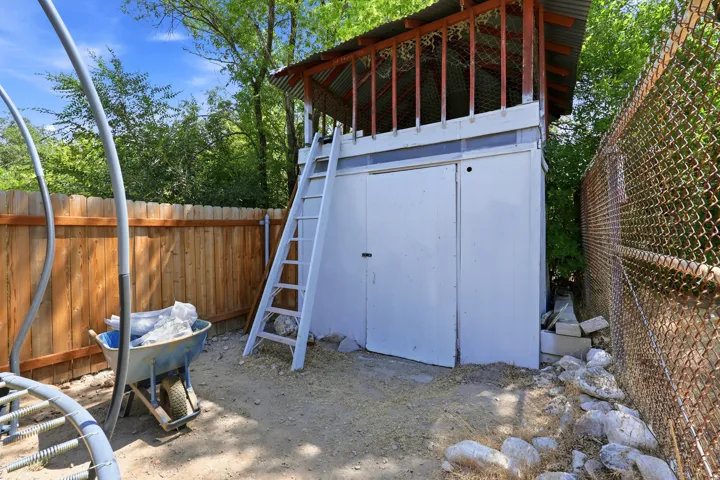 Detached two-story structure with a lower enclosed storage area and an upper open-air platform featuring a corrugated metal roof