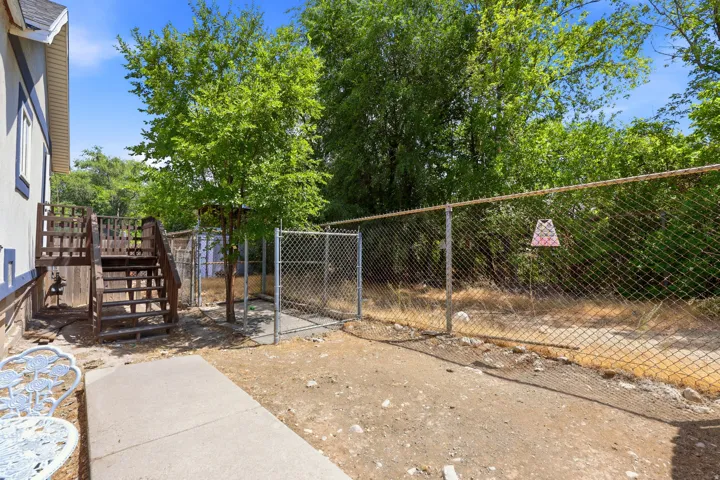 Rear exterior featuring a multi-level wooden deck, concrete patio, and mature trees